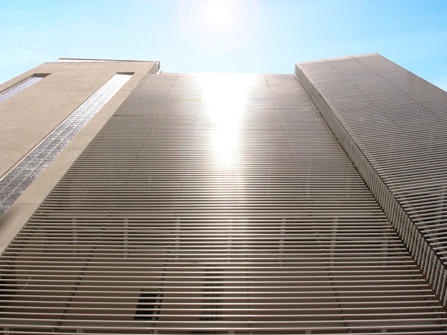 Aluminium louvres across a tower, the sun behind them